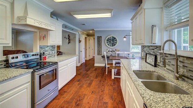 A kitchen with white cabinets, a granite countertop, a stainless steel sink, and a built-in oven. - Charming Country Getaway in Reilly Springs (Sulphur Springs)