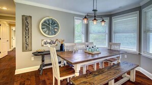 A dining area with a wooden table and benches, a clock, and a 'Farmhouse' sign on the wall. - Charming Country Getaway in Reilly Springs (Sulphur Springs)