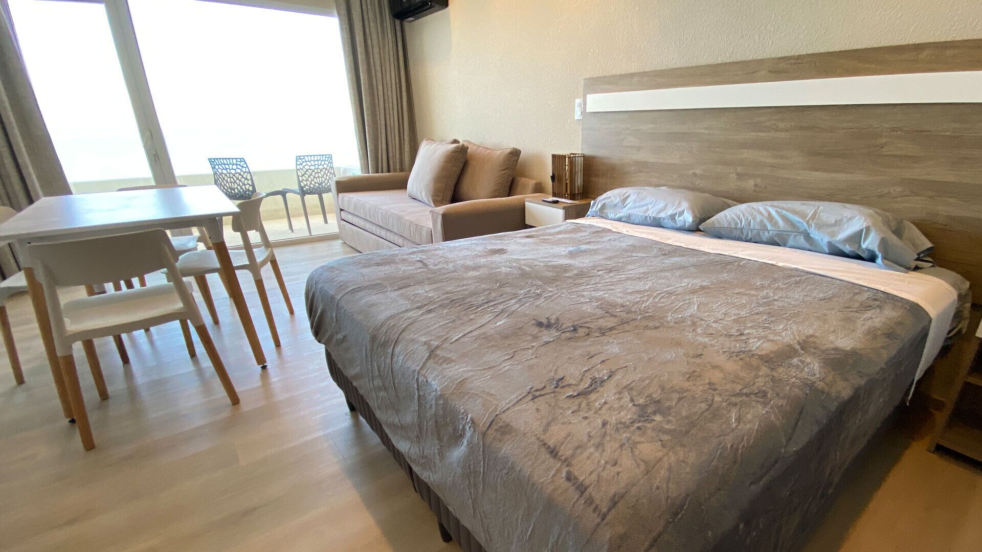Una habitación de hotel con cama, escritorio, silla y sofá.