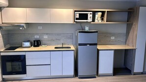 Cocina compacta con microondas, cafetera, tostadora y refrigerador.
