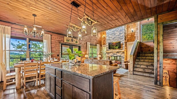 A spacious kitchen with a large island, wooden flooring, and a stone fireplace. - Ultimate Mountain Getaway Pickleball & Basketball Courts Games Hot Tub Sleeps 20 (Sevierville)