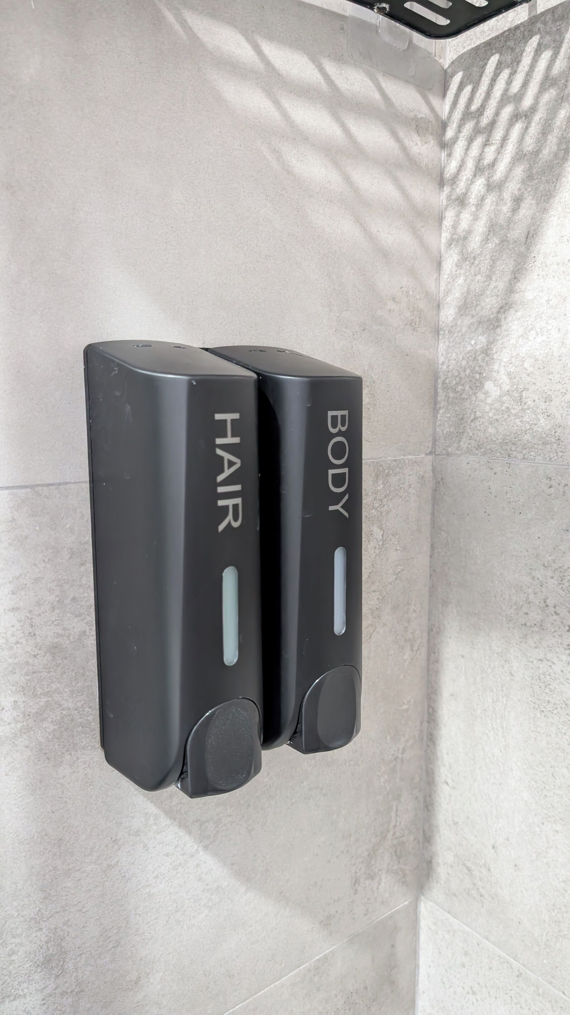 Dos secamanos negros fijados a una pared de azulejos.