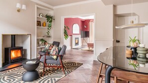 A modern living room with a fireplace, a round glass table, and a cozy seating area. - Springfield-Windermere (Windermere)