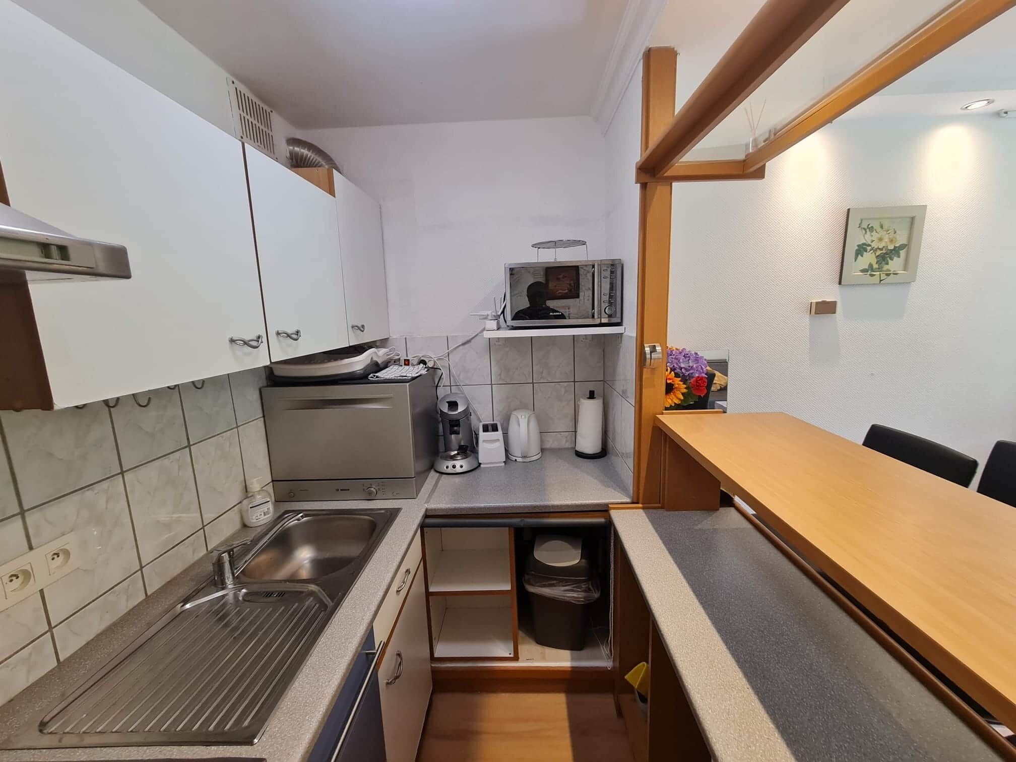 A compact kitchen with a sink, microwave, and coffee maker.