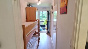 A narrow hallway with a bunk bed on the left, a door at the end, and a painting on the right wall. - Pause Nature 30N _ living in nature in peace and quiet (Kelmis)