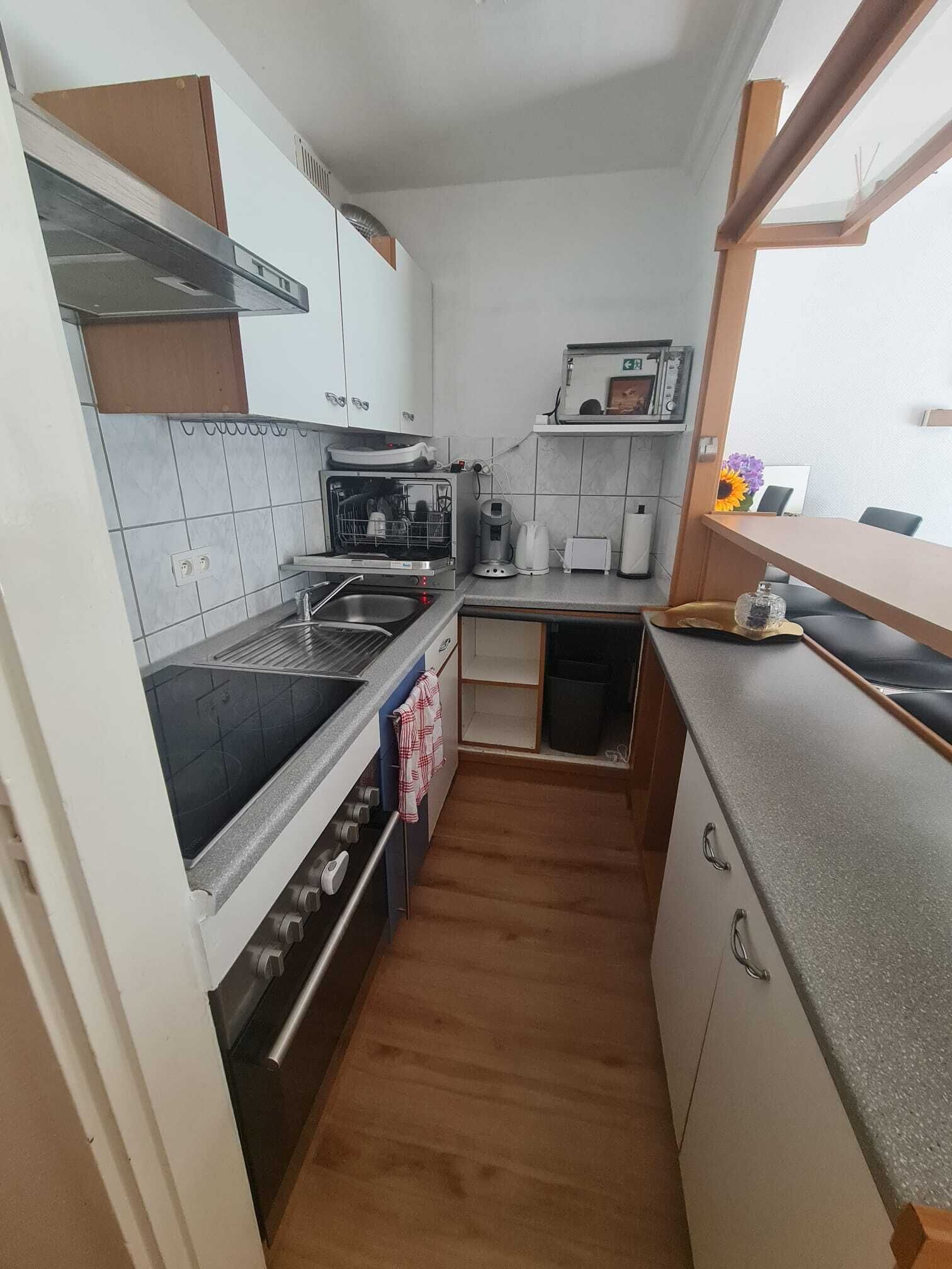 Pieni, käytännöllinen keittiö, jossa on liesi, pesuallas ja pieni työtaso.