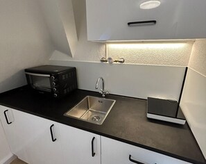 Microondas, cafetera o tetera, utensilios de cocina y mesa de comedor