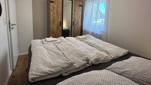 A bedroom with a large wardrobe, a bed with neatly folded blankets, and a window with sheer curtains. - Schönblick House B6 · Large Panoramic Terrace (Schöfweg)