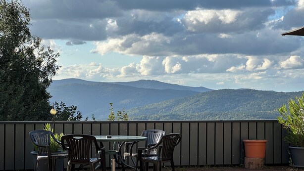 A patio with a table and chairs, a potted plant, and a view of mountains. - Schönblick House B6 · Large Panoramic Terrace (Schöfweg)