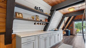 Eine Küche mit weißen Schränken, Holzbalken und einem großen Fenster.