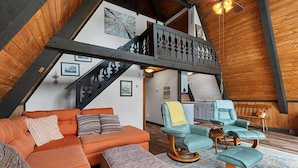 Ein Loft-Wohnbereich mit einer Holztreppe, einer Sofagarnitur und zwei Schaukelstühlen.