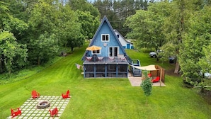 Ein blaues Haus mit einer Terrasse, umgeben von einem gepflegten Rasen und Bäumen.