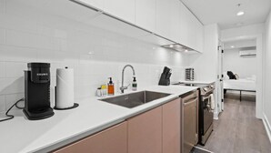 A modern kitchen with white cabinets, a coffee maker, a sink, and a dishwasher. - Columbia Heights 5BR · Sleeps 14 · Whole House (Washington)