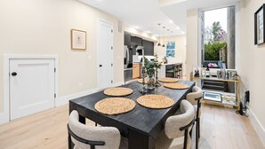 A modern dining area with a dark wooden table, four woven placemats, and six chairs.