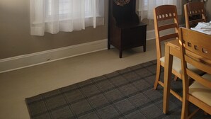 A room with two windows covered by sheer white curtains, a wooden chair, a small table, and a decorative wreath on a wall-mounted stand. - 1895 meets 2025 Townhouse in Urban Hamilton (Hamilton)