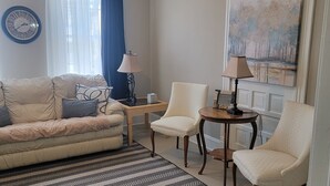 A living room with a sofa, two armchairs, a coffee table, a rug, a lamp, a clock, and a painting on the wall. - 1895 meets 2025 Townhouse in Urban Hamilton (Hamilton)