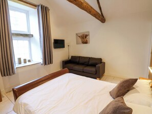 A bedroom with a bed, a sofa, a TV, and a window with curtains. - The Holt Barn (Ripon)