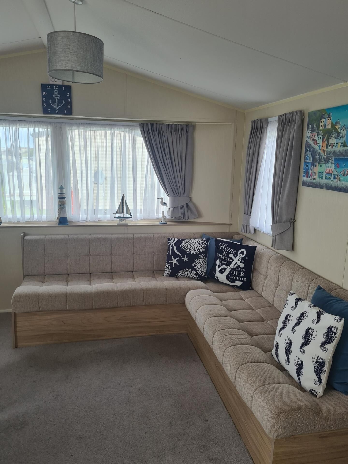 A living room with a large L-shaped sectional sofa, a ceiling fan, and a window with curtains.