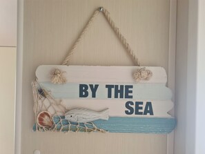 Une enseigne décorative portant l’inscription « AU BORD DE LA MER » et comportant des éléments marins, comme un poisson et un filet.