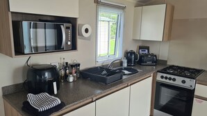 Una cocina compacta con microondas, tostadora, hervidor y estufa.
