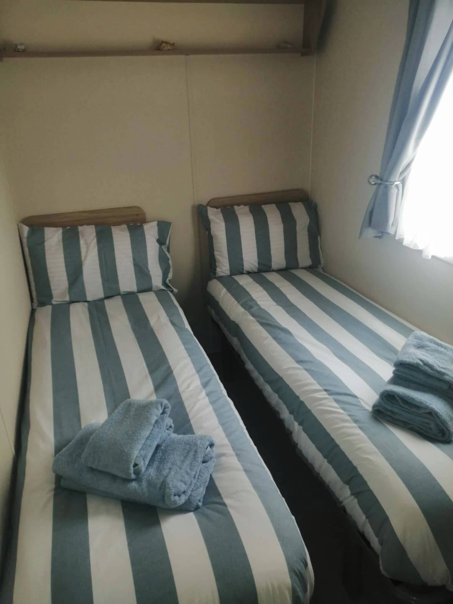 Two single beds with striped bedding and a folded towel on one bed.
