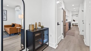 Een moderne hal met een zwarte console tafel, een grote spiegel en een bank op de achtergrond.