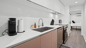 Een moderne keuken met witte kastjes, een koffiezetapparaat, een spoelbak en een vaatwasser.