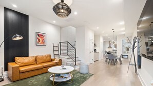 Ein modernes Wohnzimmer mit einer Ledersofa, einem runden Couchtisch und einer Treppe, die zur Küche führt.