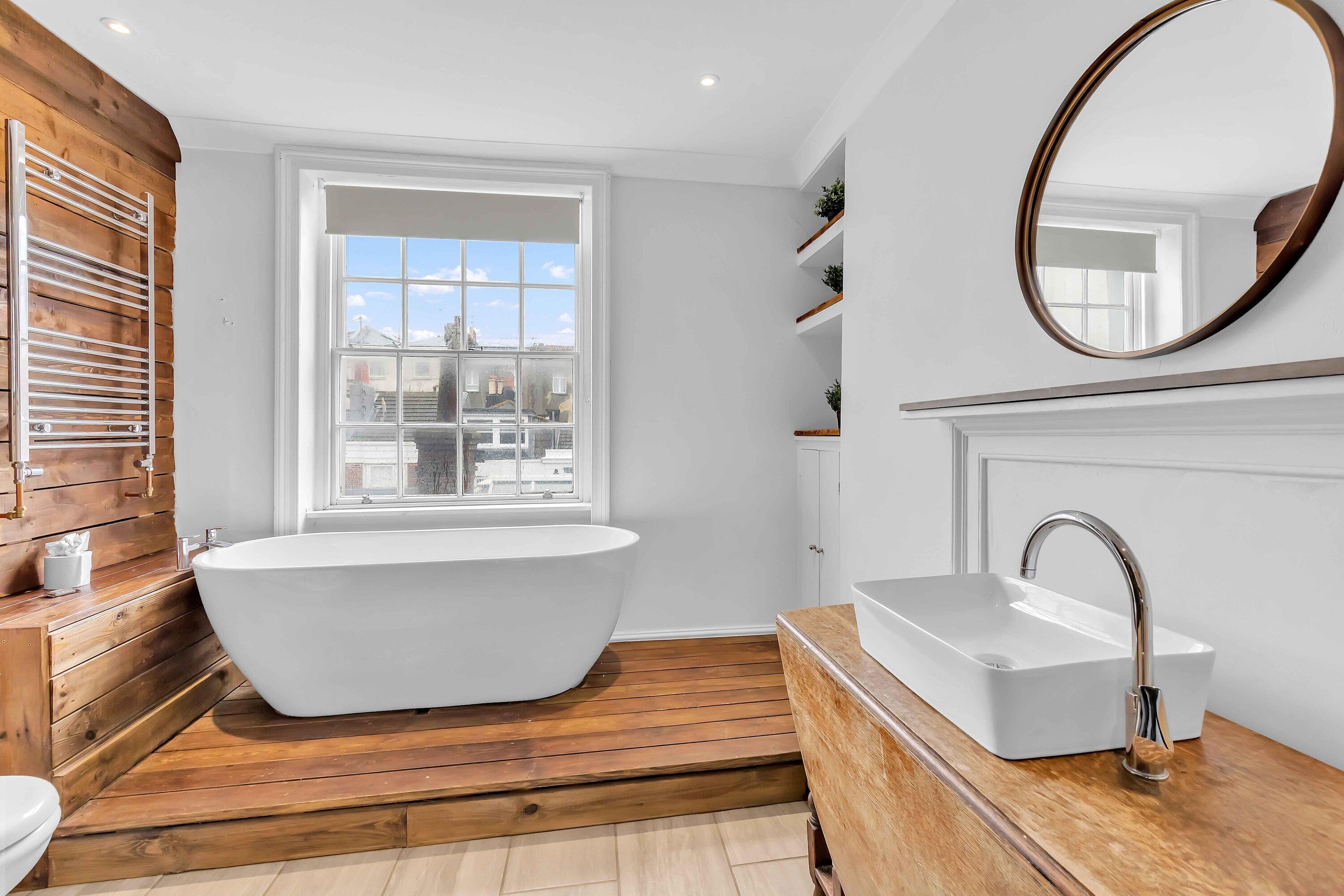 A modern bathroom with a freestanding bathtub, a white sink, and a large mirror.