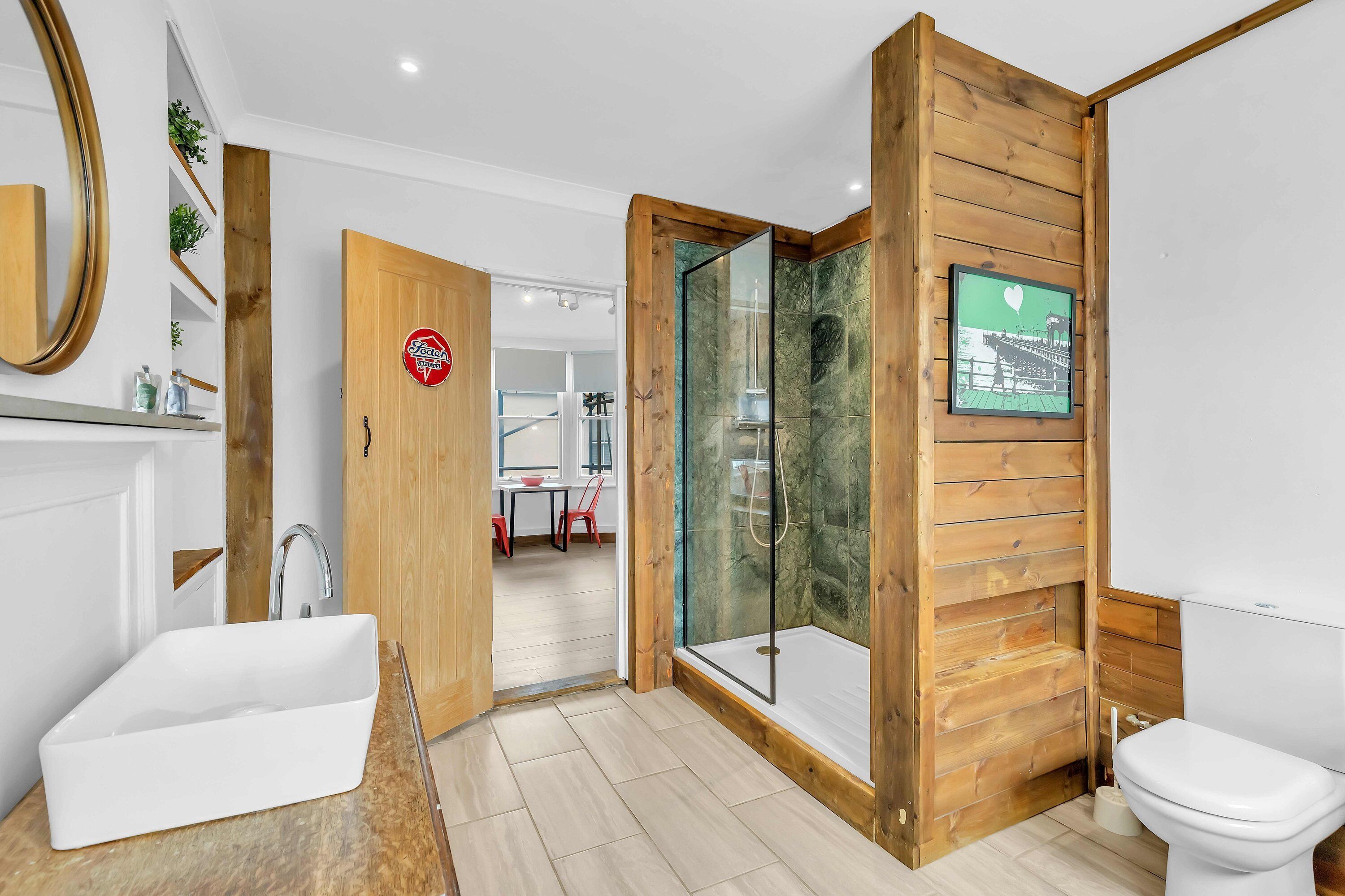 A modern bathroom with a wooden vanity, a glass shower enclosure, and a toilet.