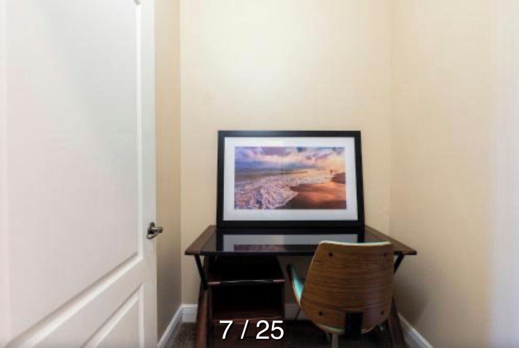 A room with a desk, a chair, and a framed picture on the wall.