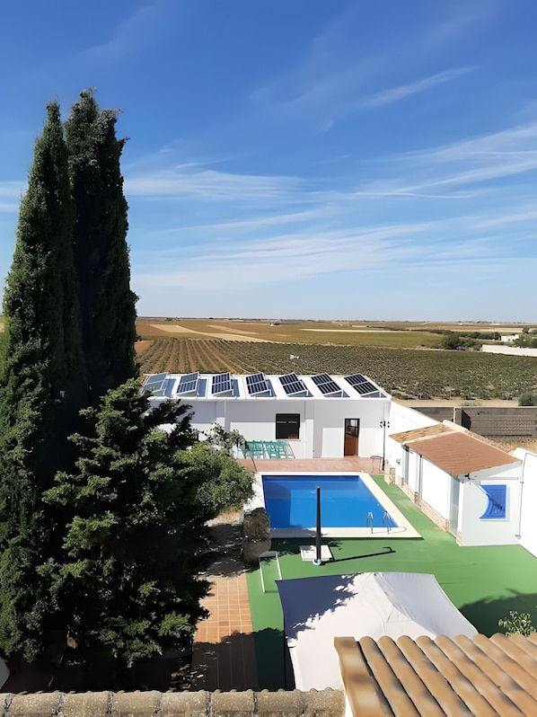 A modern villa with a swimming pool, solar panels, and a view of the countryside.