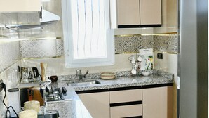 A modern kitchen with granite countertops, stainless steel appliances, and beige cabinetry. - Charming 2-bedroom flat 10 minutes to the beach (Agadir)
