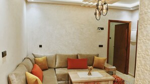 A living room with a beige sofa, a wooden coffee table, and a small decorative item on the table. - Charming 2-bedroom flat 10 minutes to the beach (Agadir)