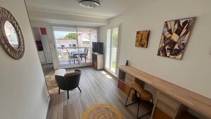 Een modern interieur met een houten vloer, een rond geweven vloerkleed, een zwarte stoel, een houten bureau en een televisie.