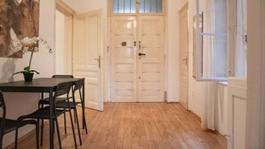Een kamer met een houten vloer, een eettafel met stoelen, een potplant en een paar dubbele deuren.