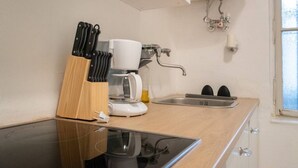 Een keuken met een koffiezetapparaat, messen en een spoelbak.