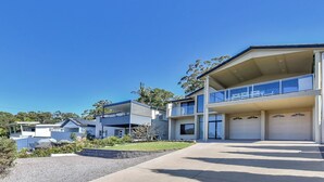 A modern two-story residential building with a balcony, a garage, and a well-maintained garden. - Oasis at Salamander Bay (Salamander Bay)