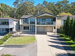 A two-story residential building with a garage, a covered patio, and a well-maintained lawn.