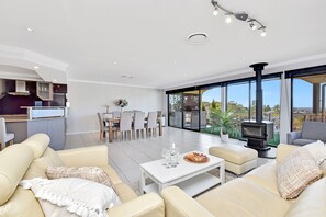 A modern living room with a fireplace, a dining area, and a kitchen.