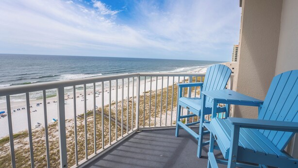 A balcony with a view of the beach and ocean.