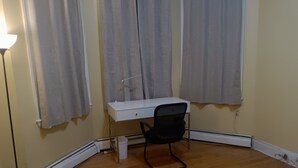 A room with a white desk, a black office chair, a standing lamp, and a heater. - Charming 2-bedroom apartment in Cleveland Circle Boston, Near BC, BU (Boston)