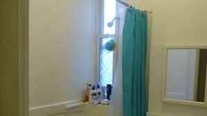 A bathroom with a bathtub, a sink, and a window with a shower curtain. - Charming 2-bedroom apartment in Cleveland Circle Boston, Near BC, BU (Boston)