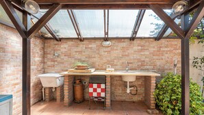 A brick kitchen with a sink, a stove, and a window.