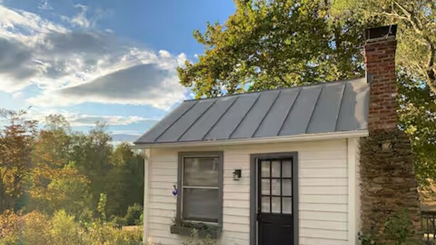 A small, single-story house with a metal roof, a black front door, and a window. - Cozy Cottage Perfect for a Charming Charlottesville (Charlottesville)