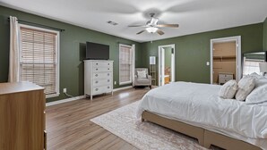 Quarto com cama, penteadeira, televisão e ventoinha no teto.