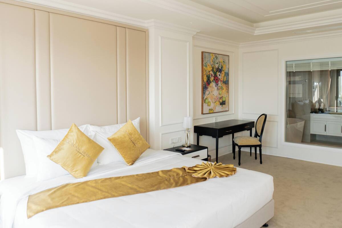 Una habitación de hotel con una cama grande, un escritorio, una silla y un cuadro en la pared.