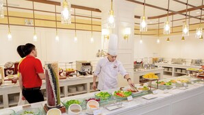 A buffet setup with various food items and a chef preparing food.