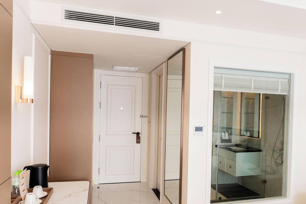 Habitación de hotel con baño, puerta, zona de café y cabina de ducha.