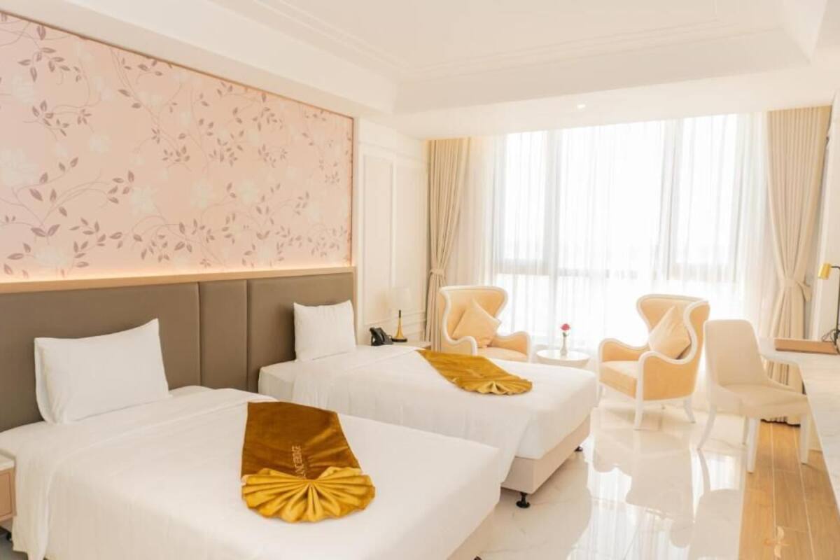 Una habitación de hotel con dos camas, un ventanal grande, un sofá y una silla.